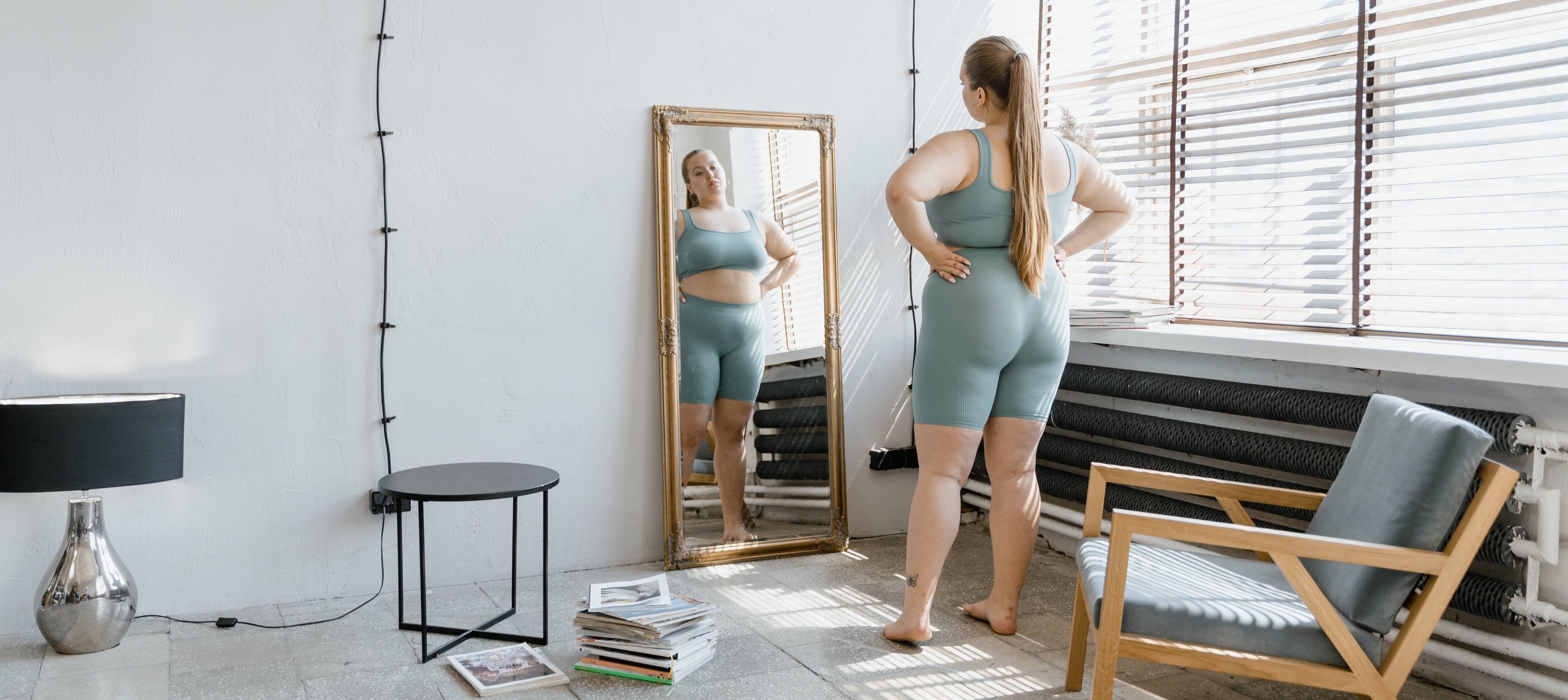 Eine übergewichtige Frau schaut in den Spiegel